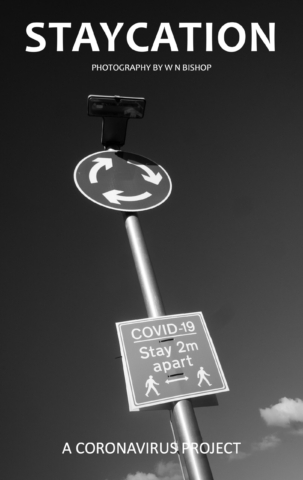 A mini island road sign with a 'Covid-19 Stay 2m apart' sign attached to it.