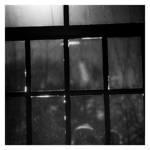 Looking out of one of the wooden huts through iron window frame